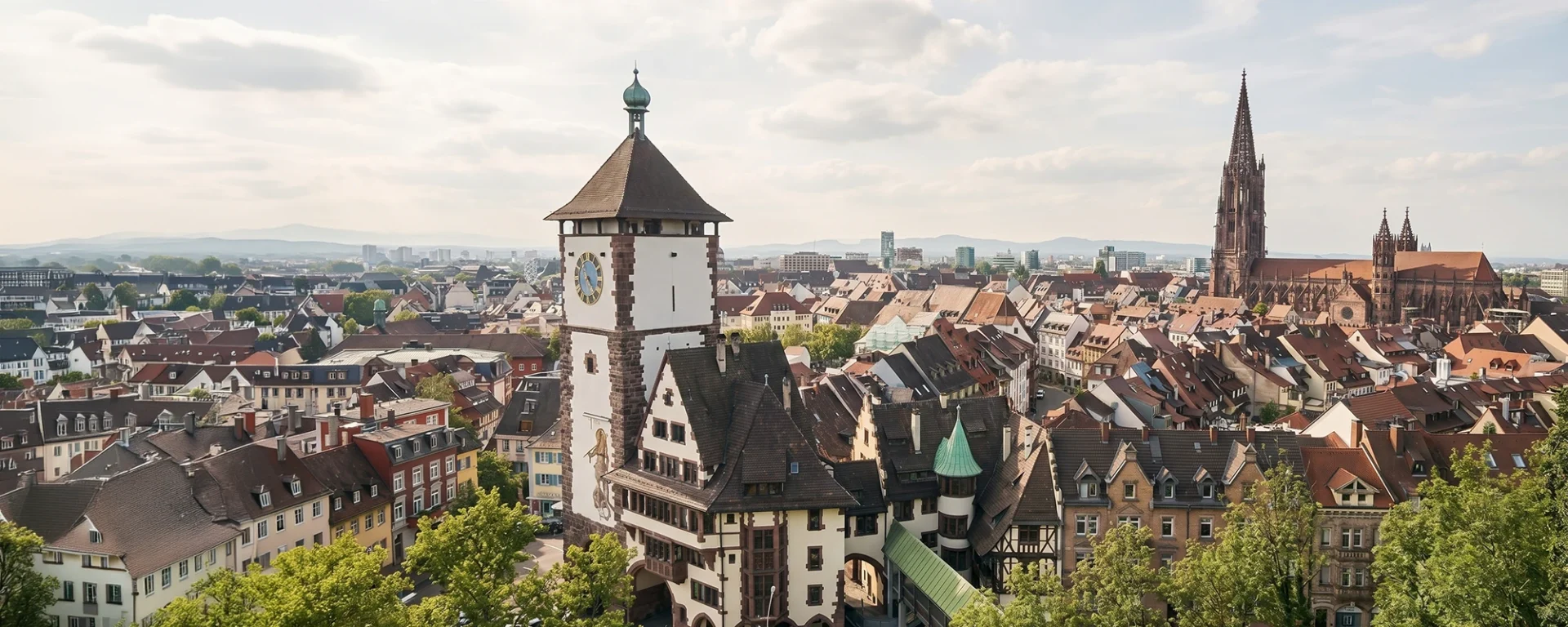 Panorama von Freiburg: Historischer Martinstor-Turm und der beeindruckende Freiburger Münster im Hintergrund unter blauem Himmel als Visualisierung für Online Marketing aus Freiburg.