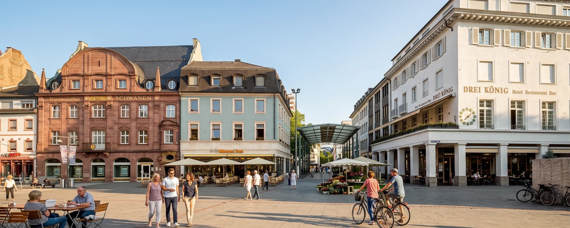 Marktplatz Lörrach mit historischen Gebäuden und Menschen, die spazieren und in Straßencafés sitzen, sonniger Tag.