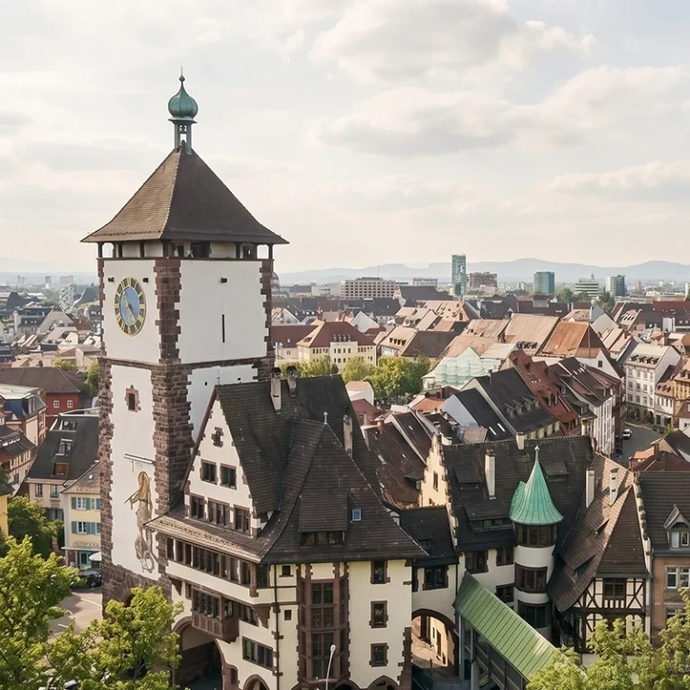 Panorama von Freiburg: Historischer Martinstor-Turm und der beeindruckende Freiburger Münster im Hintergrund unter blauem Himmel als Visualisierung für Online Marketing aus Freiburg.