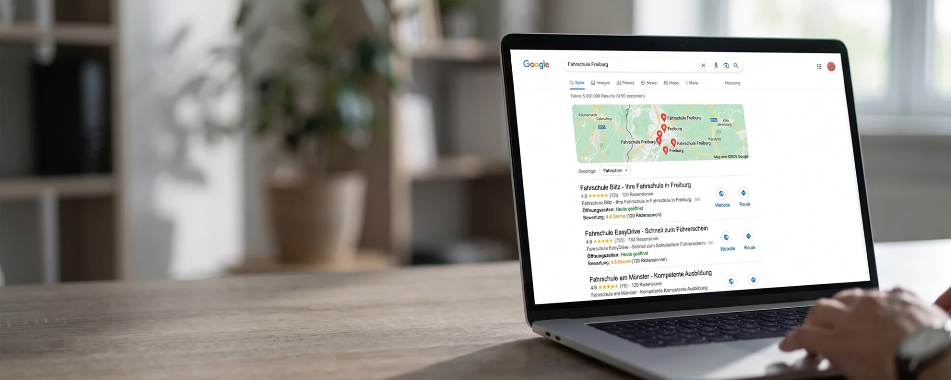 Laptop zeigt Google-Suche nach Fahrschule Freiburg mit lokalen Ergebnissen und Karte auf dem Bildschirm.