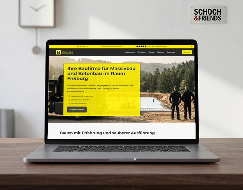 Laptop zeigt Webseite einer Baufirma für Massiv- und Betonbau in Freiburg, mit zwei Bauarbeitern und Baustelle im Hintergrund.